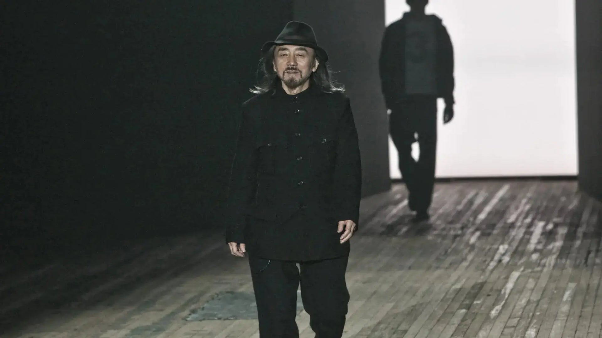 Man in black fedora and coat exemplifying Japanese fashion style