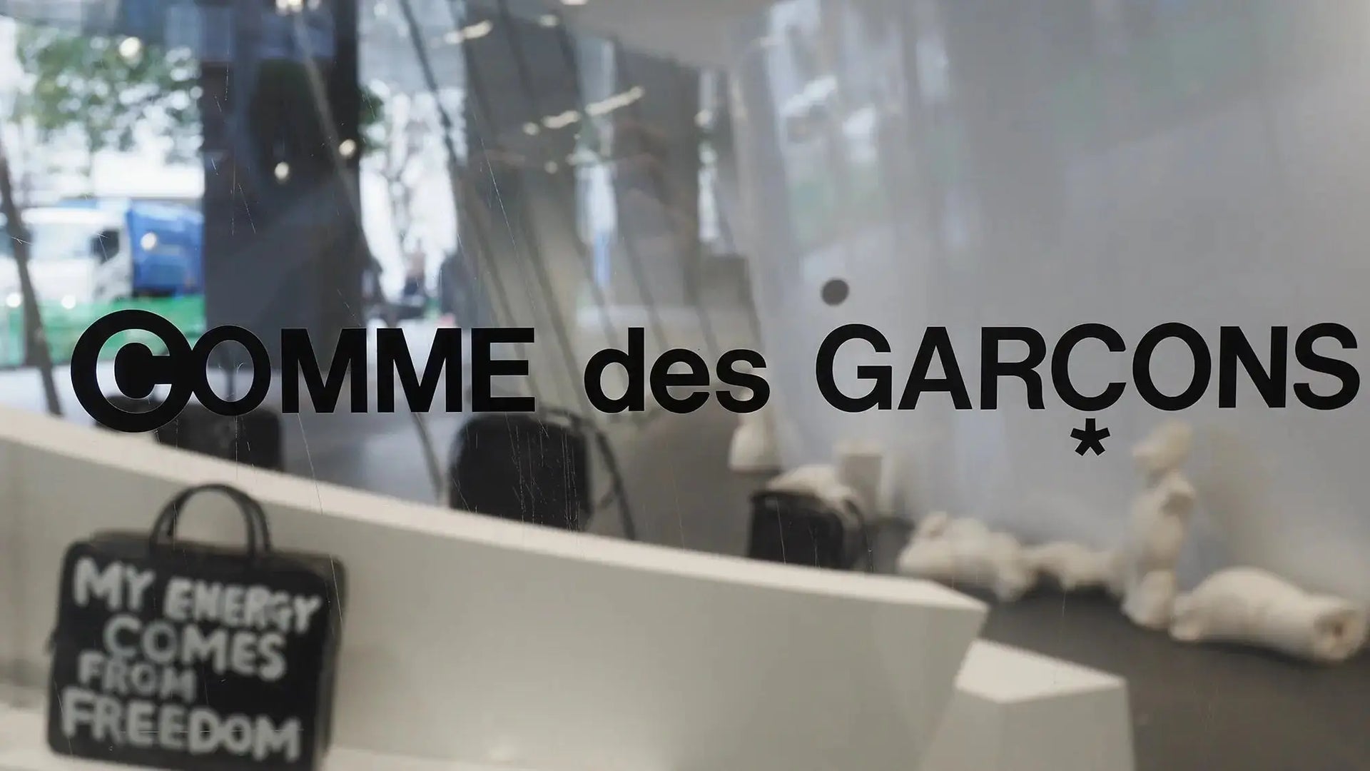 Black handbag with white embroidered text my energy comes from freedom by Rei Kawakubo