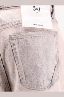 Light-wash blue 3x1 women’s denim jeans with faded distressed texture and white brand tag on waistband