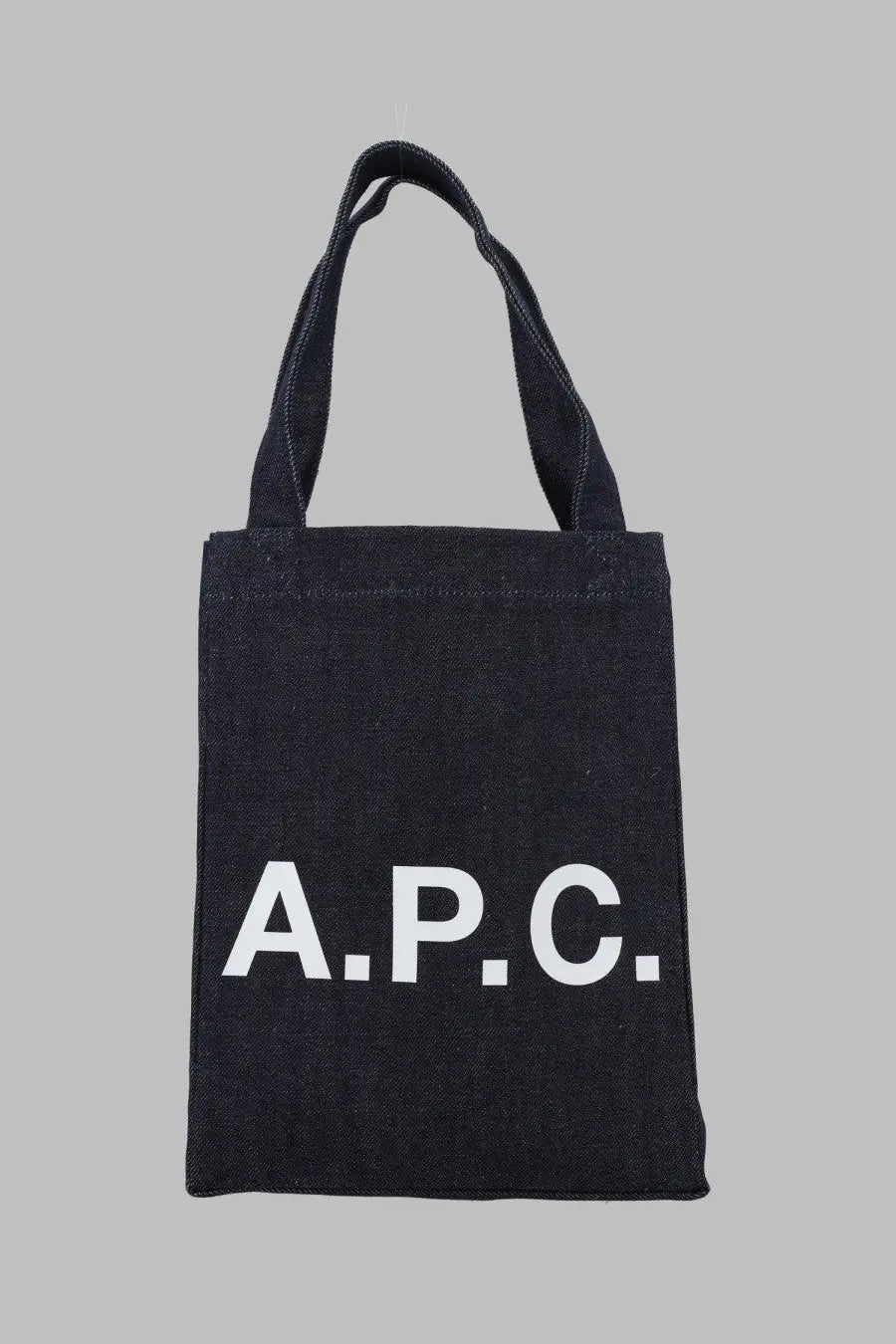 Black canvas a.p.c tote bag with bold white lettering in a small blue style for women