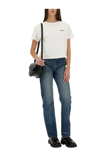 Black leather crossbody bag with minimalist design and rounded flap closure alongside A.P.C women’s kylie blue jeans