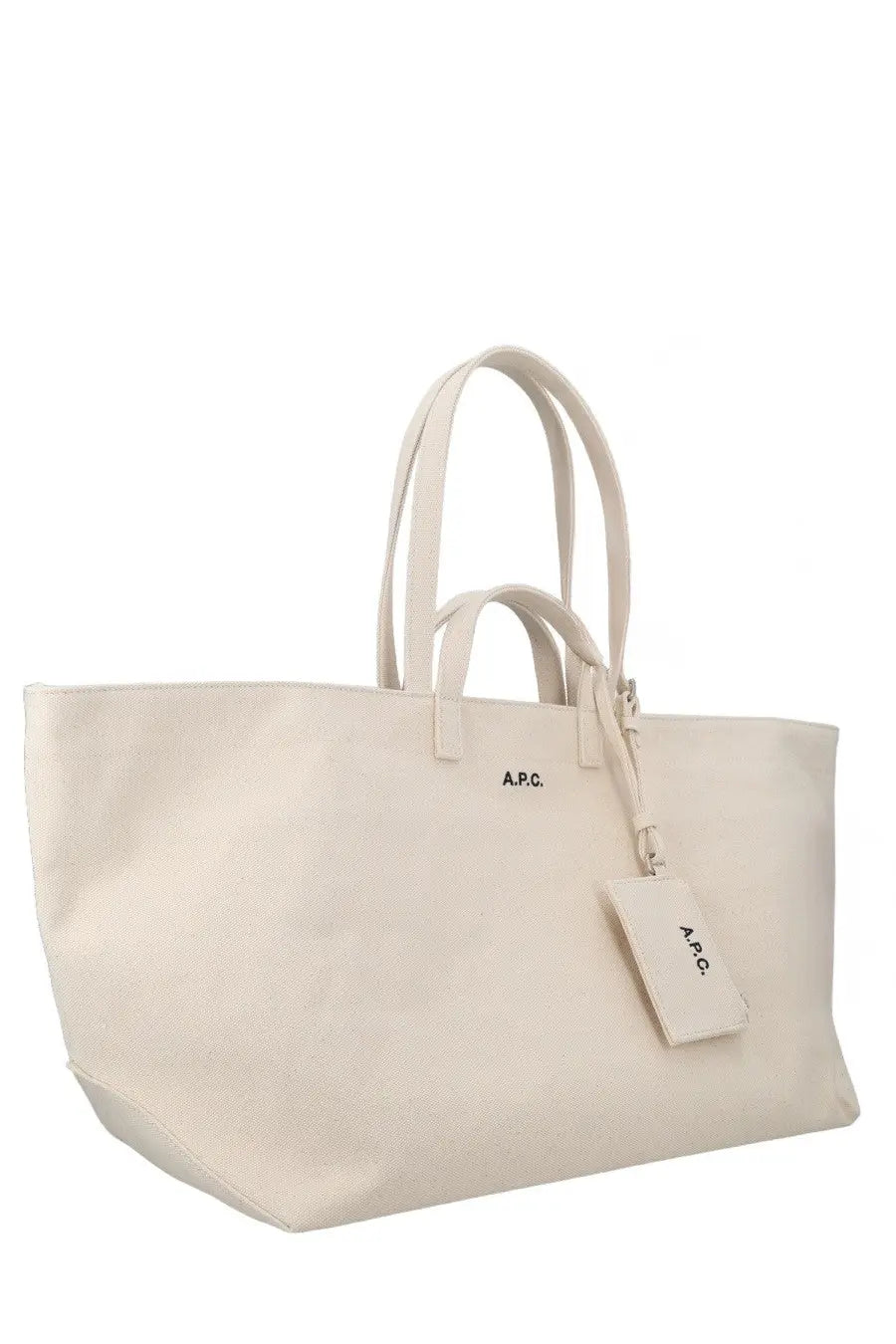 Cream-colored canvas a.p.c women’s le drummer tote bag with matching leather handles and small brand tag in pink