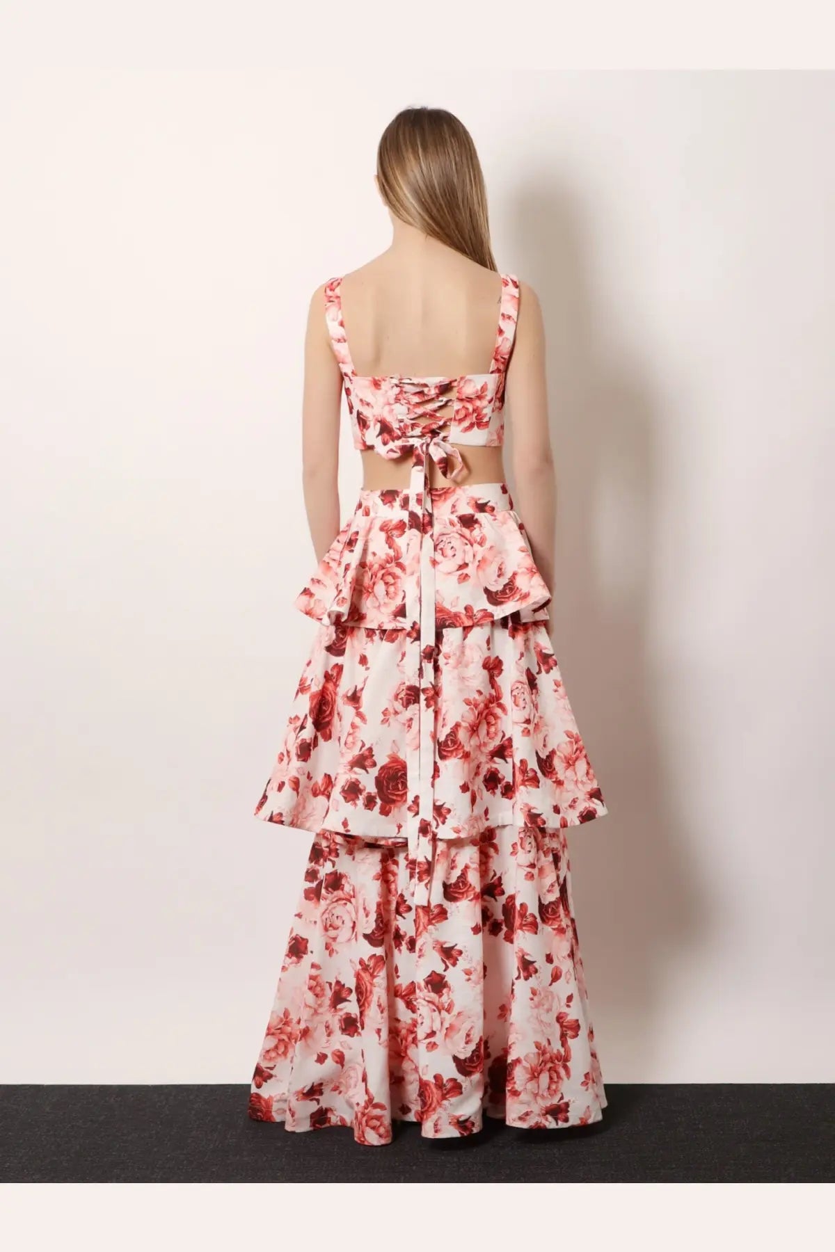 A woman wears an actualee women’s flounced long skirt pink with tiered ruffles and pink red rose floral pattern