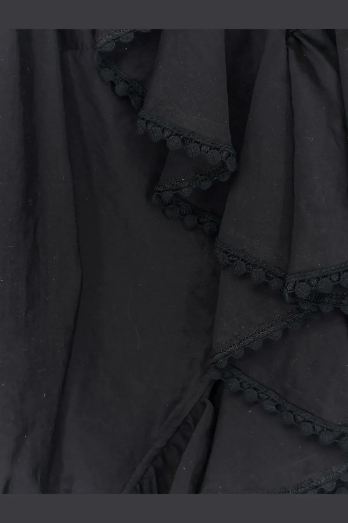 Actualee women’s black shirt featuring ruffled fabric with delicate black pom-pom trim along the edges