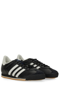 Adidas men’s kick sneaker black with three white stripes black laces and gum-colored rubber sole visible from front