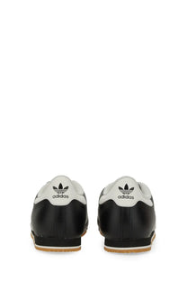 Adidas men’s kick sneaker black showing back side of black and white samba leather upper with trefoil logo heel