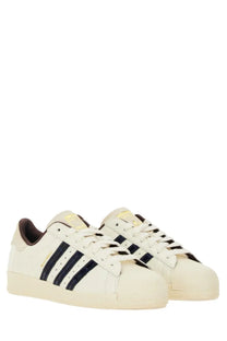 Cream-colored adidas Originals by Wales Bonner superstar sneakers with navy blue stripes and matching rubber toe cap