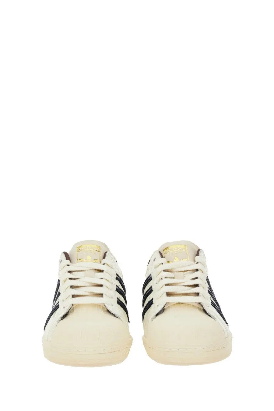 Cream-colored adidas Originals by Wales Bonner men’s Superstar sneakers with black stripes and gold-toned branding