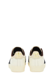 Back view of cream-colored adidas Originals by Wales Bonner men’s sneaker superstar with black stripes and gold trefoil logos