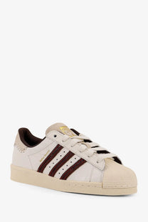 Cream-colored leather adidas Originals by Wales Bonner men’s WB Superstar sneakers with maroon glitter stripes and gold branding