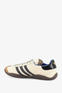Cream-colored adidas Originals by Wales Bonner unisex WB Karintha OG leather sneaker with black stripes navy heel tab and gold logo
