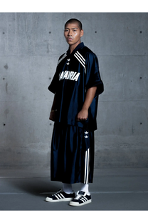 Navy blue satin adidas track set with white stripes and logo detailing paired with black nylon adidas originals x willy chavarria sneakers