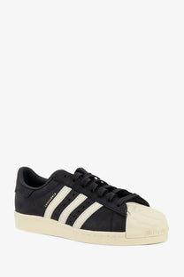 Adidas originals x willy chavarria men’s black suede leather superstar sneaker with three white stripes and cream toe cap
