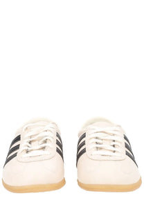 White adidas unisex gazelle lo pro sneaker with black three stripes and tan rubber sole in beige color