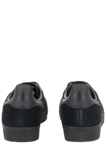 Black adidas unisex gazelle sneaker with suede and leather upper featuring iconic three-stripe design on the side