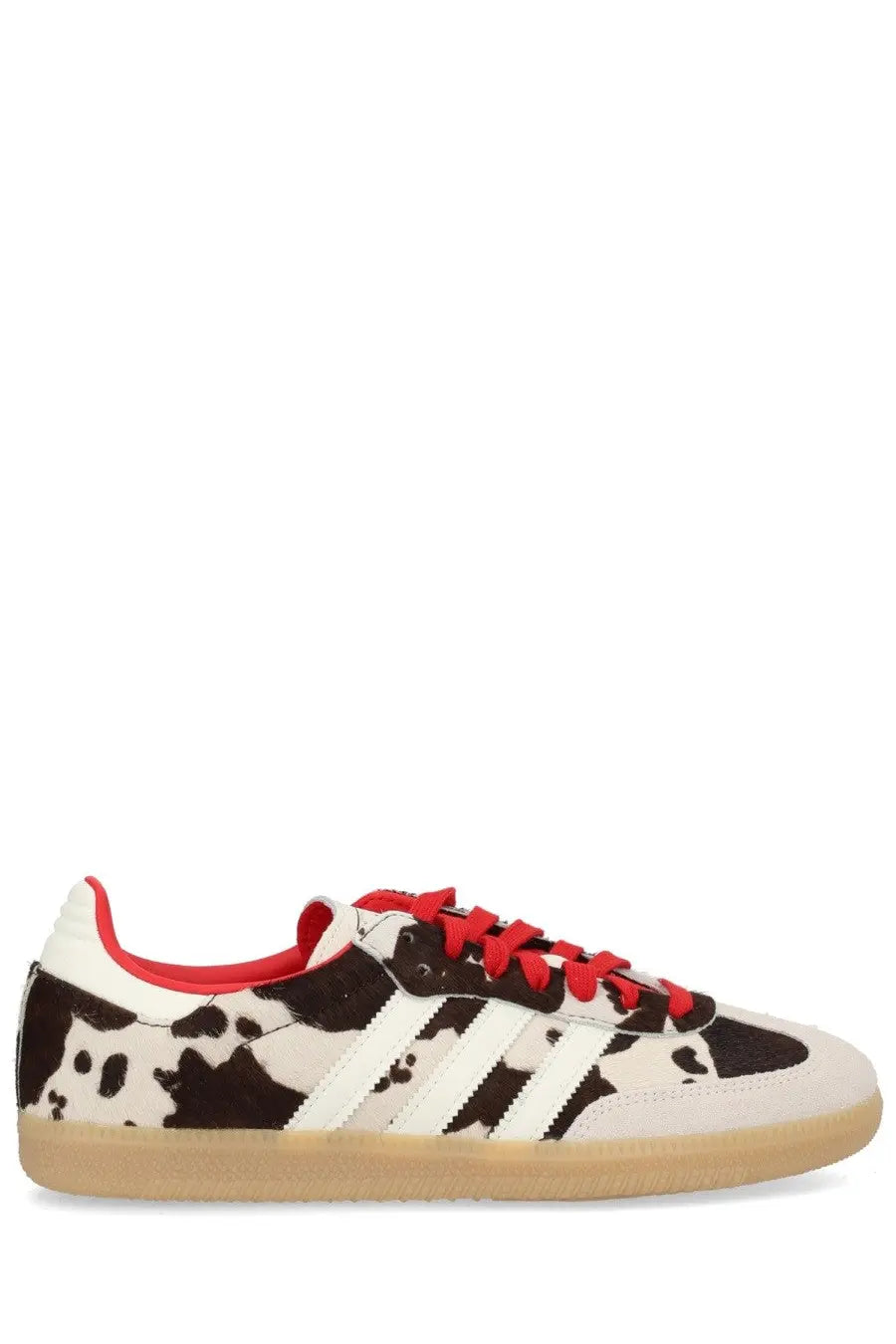 Adidas unisex samba og sneaker with black and white cow print upper, red laces and lining, and white three stripes