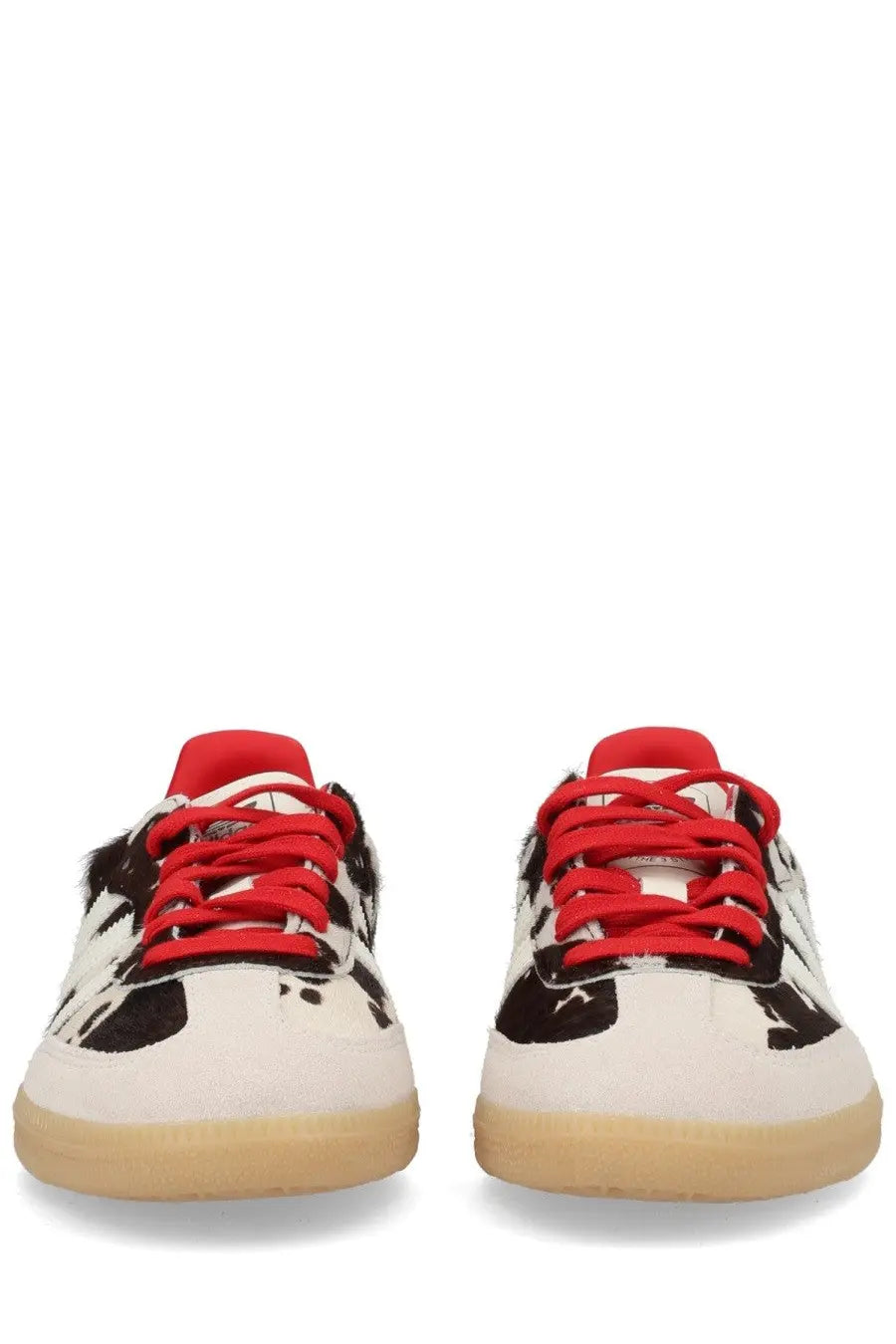Adidas unisex Samba OG sneaker with white black cow print, red laces and tongue, and tan rubber sole