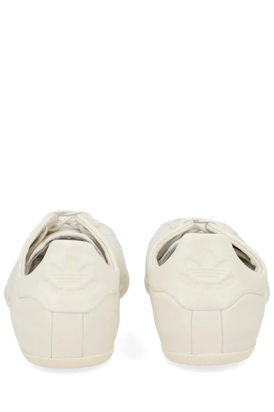 Cream-colored leather adidas superstar sneakers with classic three-stripe design on the heel shown from the back side