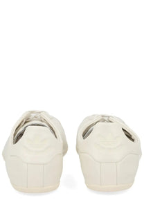 Cream-colored leather adidas superstar sneakers with classic three-stripe design on the heel shown from the back side