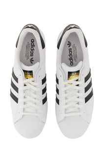 White adidas unisex superstar sneaker featuring black three stripes and gold branding accents in leather design