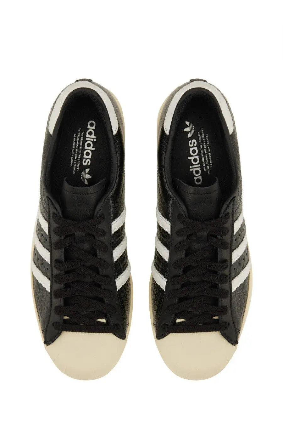 Black adidas unisex superstar vintage sneaker with white three stripes and cream rubber toe cap in leather