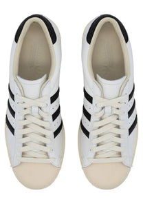 White leather adidas unisex superstar vintage sneaker with black three stripes and cream rubber toe caps