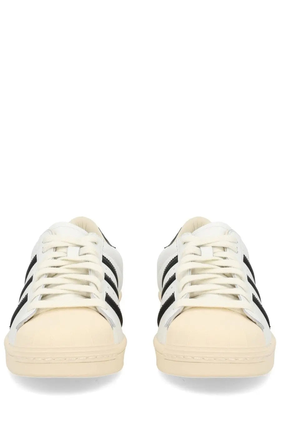 White adidas unisex superstar vintage sneaker with black three stripes and cream rubber sole