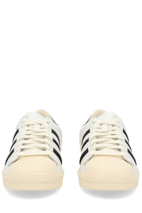 White adidas unisex superstar vintage sneaker with black three stripes and cream rubber sole