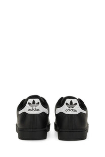 Black adidas unisex superstar sneaker showing back side with white rubber toe caps and trefoil logo on heel