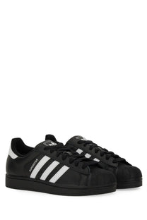 Black adidas unisex superstar sneaker featuring white three-stripe detailing and textured rubber toe cap