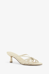 Cream-colored leather mule sandal with slender heel and crisscross straps from Aeyde women’s Abby collection white
