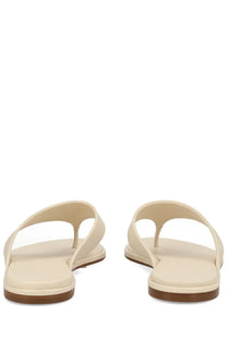 Aeyde women’s cream-colored leather thong sandal with flat sole and brown rubber heel in white