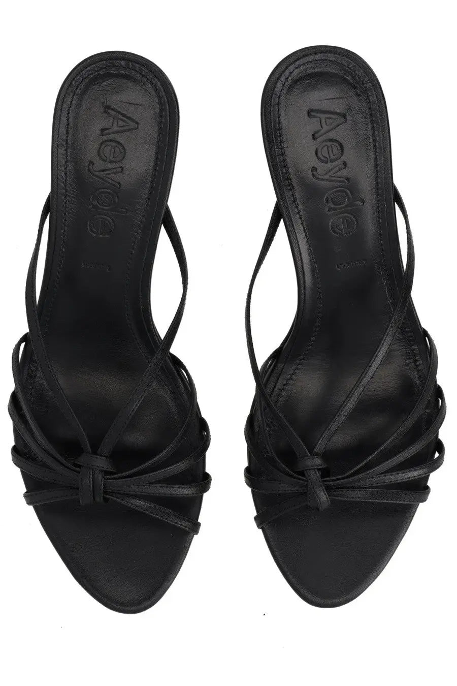 Black leather aeyde sandals with crisscross straps and a tied bow at the front.