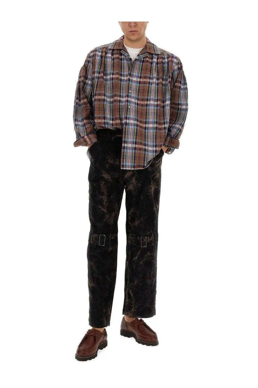 A man wearing a brown blue and white plaid shirt with aïe men’s black ribbed distressed pants