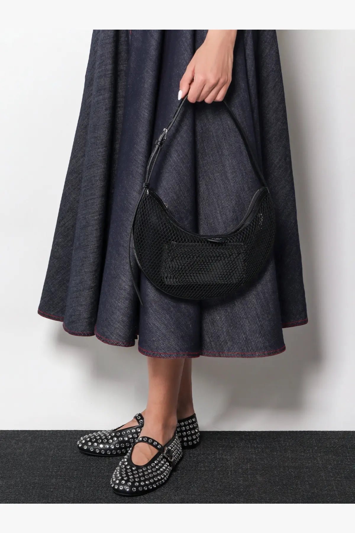 Alaïa black mesh crescent shoulder bag with subtle texture and minimalist design paired with leather ballet flats