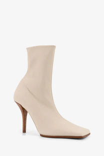 Alaïa women’s leather ankle boot in beige with a cream-colored sleek design square toe and slender wooden heel