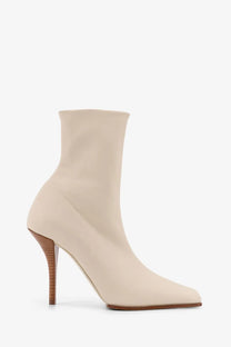 Alaïa women’s leather cream-colored sock boot with sleek minimalist design and slender wooden heel