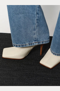 Alaïa women’s cream-colored square-toe ankle boots with slender wooden heel and smooth leather upper in beige