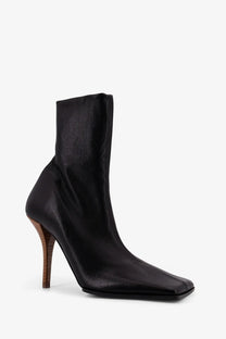 Alaïa women’s black leather ankle boot with a square toe and wooden heel seen from the back side