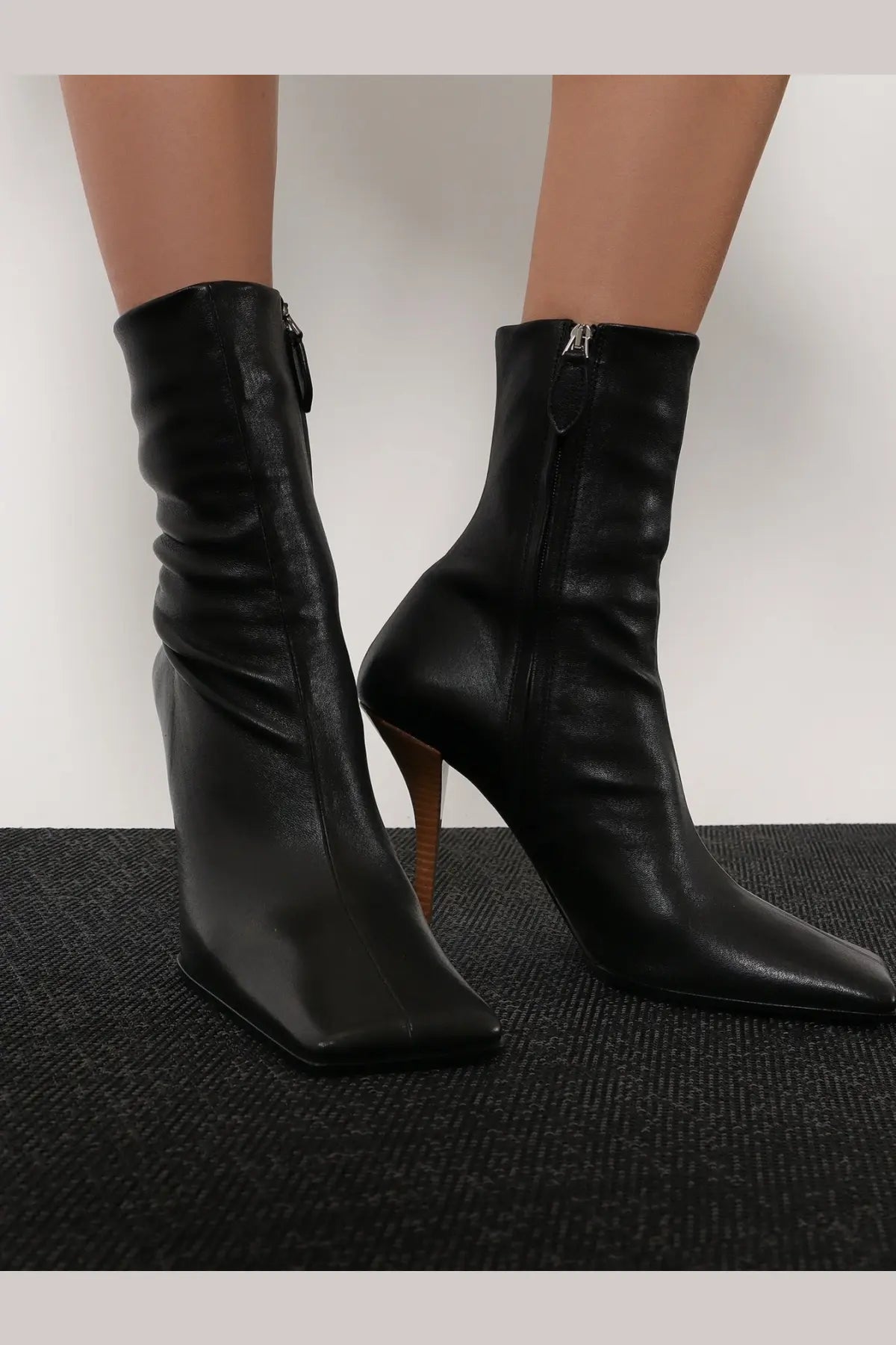 Alaïa women’s black leather ankle boots with a sleek square-toe design and slender high heel