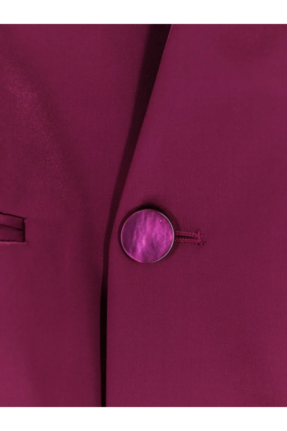 A round metallic magenta button with iridescent finish on the seam of an alberta ferretti purple satin blazer