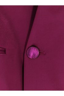 A round metallic magenta button with iridescent finish on the seam of an alberta ferretti purple satin blazer
