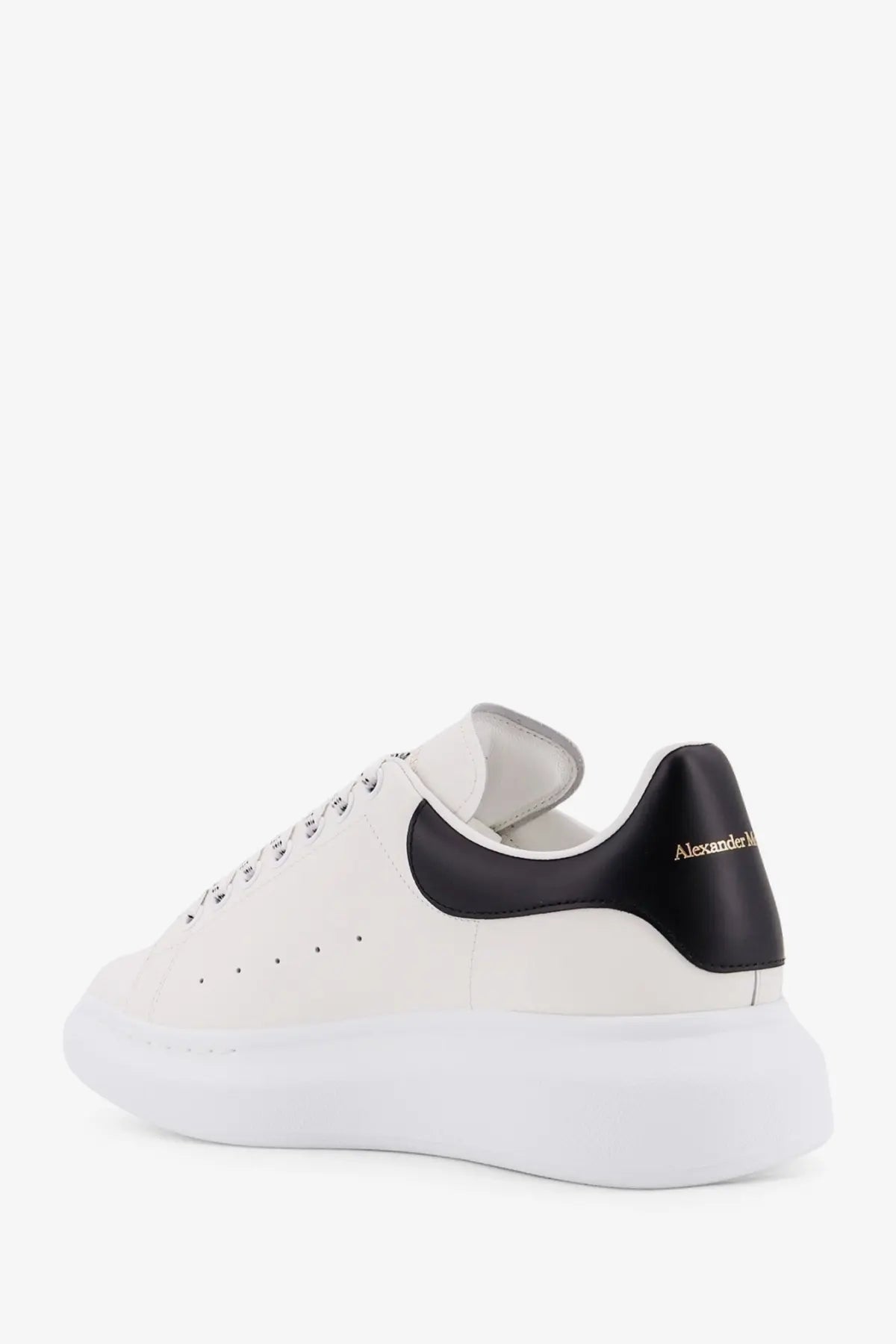Alexander McQueen men’s low top white leather sneakers with black heel tab and gold branding visible from back side