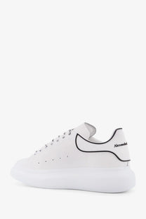 Back view of white leather alexander mcqueen men’s oversized low top sneaker with black piping and heel branding