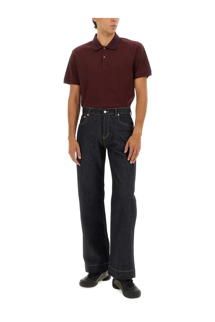 Dark indigo denim jeans with a straight-leg cut and white stitching paired with alexander mcqueen men’s red polo shirt