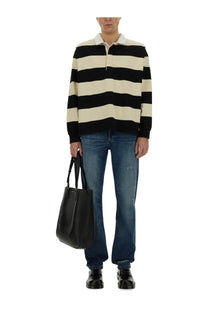 Black leather tote bag with top handles paired with Alexander McQueen men’s multicolor rugby polo shirt