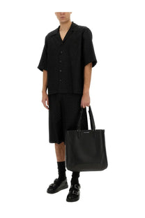 Black leather tote bag with structured design and top handles paired with Alexander McQueen skull pattern shirt black