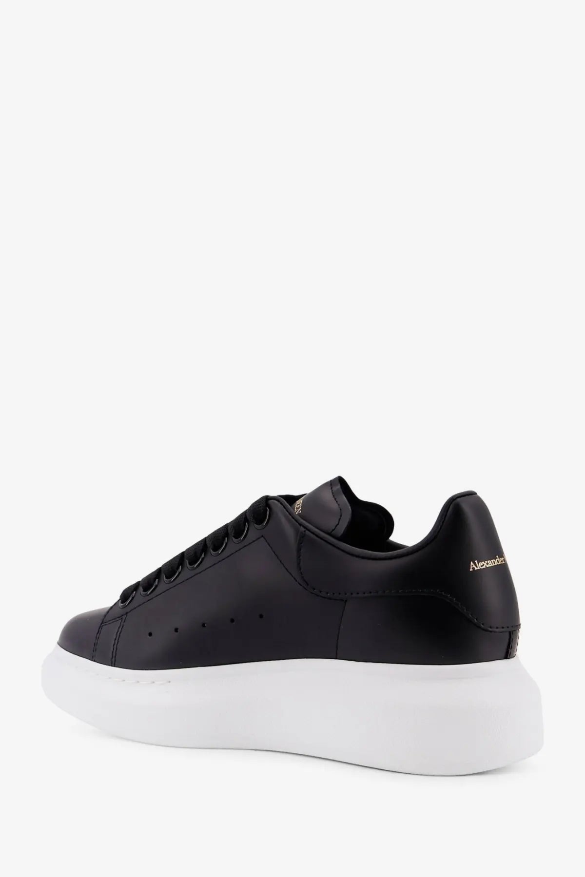 Back view of black leather alexander mcqueen women’s oversized sneakers with thick white sole and gold heel branding