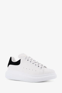 White Alexander McQueen women’s oversized leather sneaker with black heel tab and silver toned laces shown from back