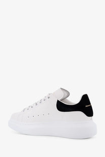 White leather Alexander McQueen women’s oversized sneaker with black suede heel tab and matching laces side view
